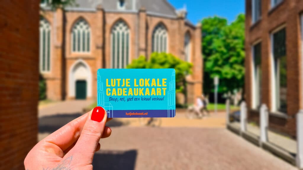 Iemand houdt de Lutje Lokale Cadeaukaart voor de Martinikerk in Groningen